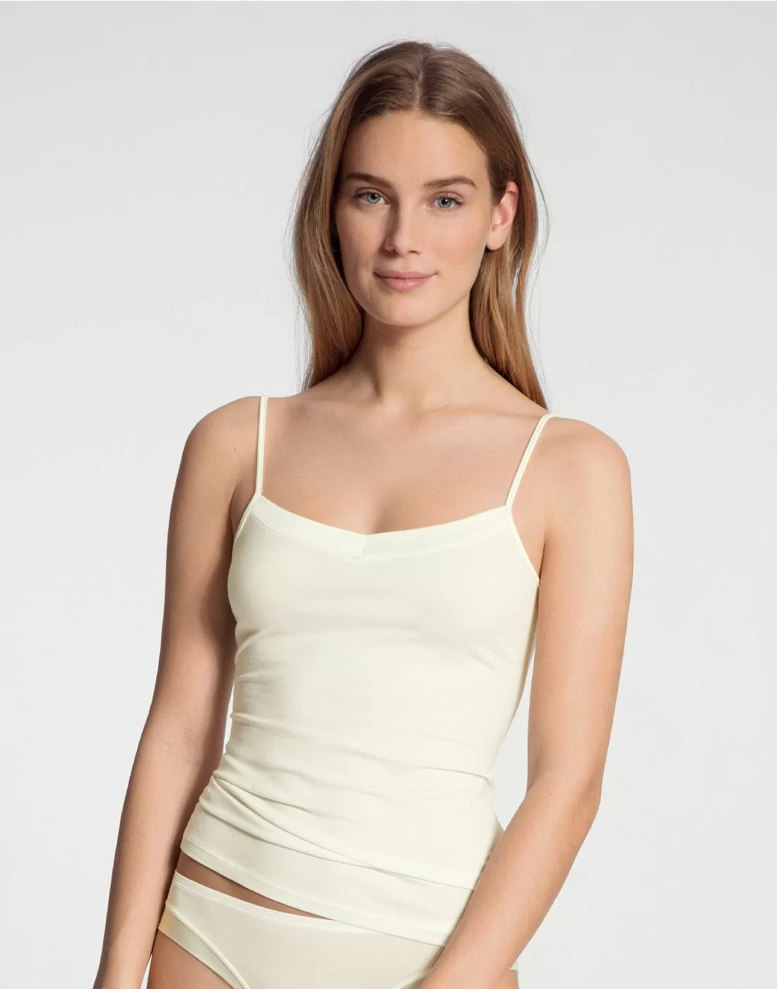 blond kvinne med spaghetti topp i creme farge