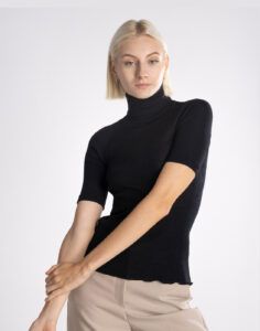 blond kvinne i svart høyhalset t-skjorte av ull og silke
