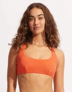 jente med brukt krøllete hår og oransje bikinitopp