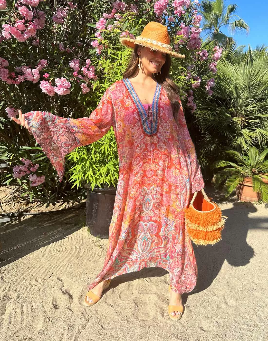 jente soler seg med stråhatt, veske og strandkjole