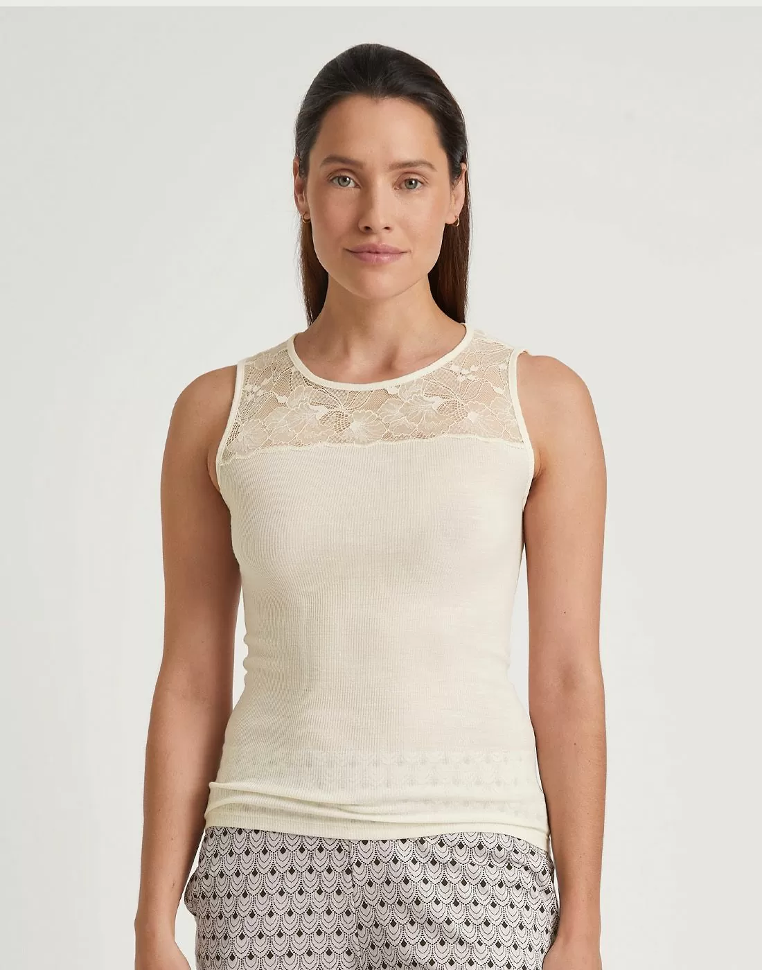 jente med brunt hår og hvit ull og silke topp med blonder