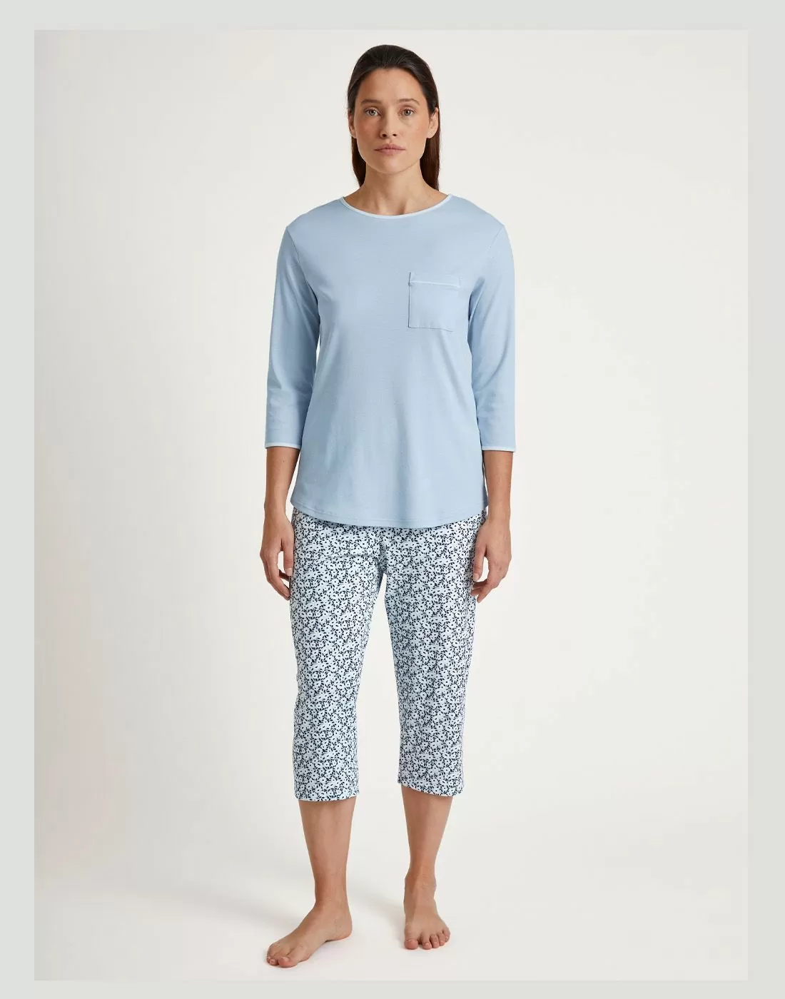 kvinne med pysj i bomull med blå genser og mønstret bukse