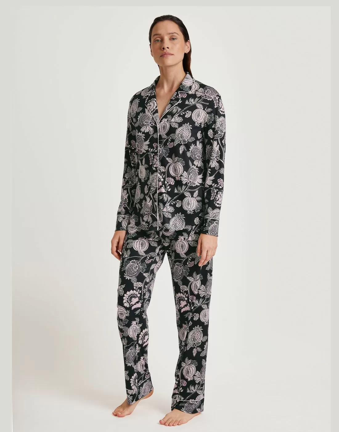 kvinne med brunt hår og pysjamas med skjorte og bukse i mønster