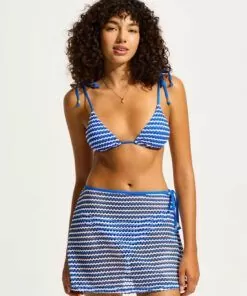 Mørkhåret kvinne med blå bikini og skjørt