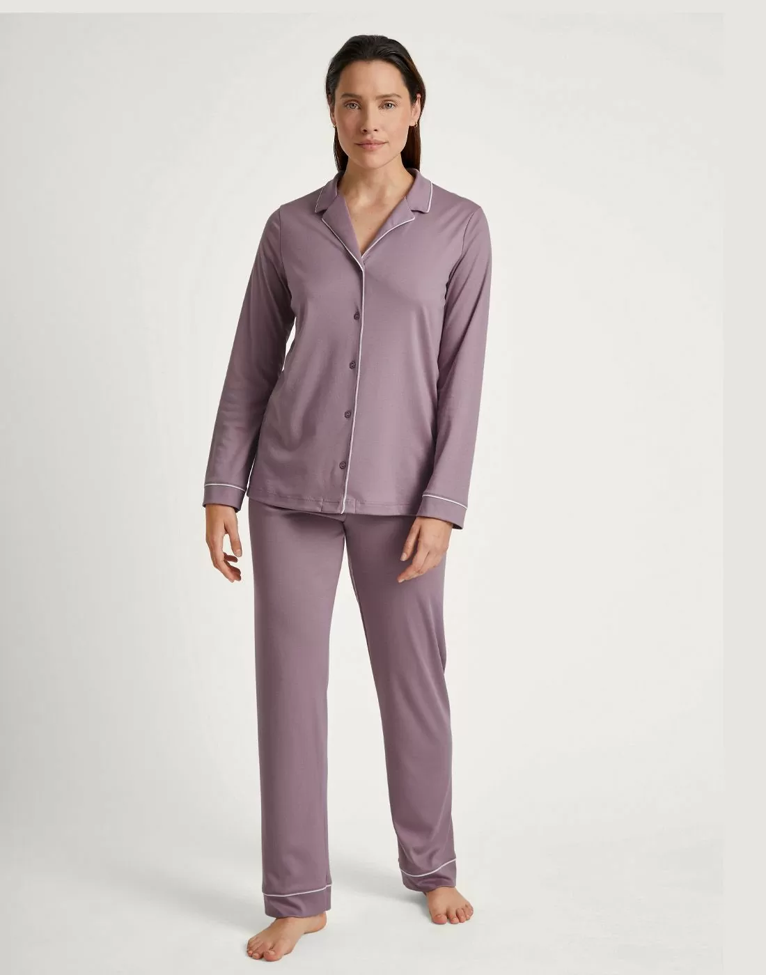 mørk kvinne i rosa pysj med skjorte og bukse