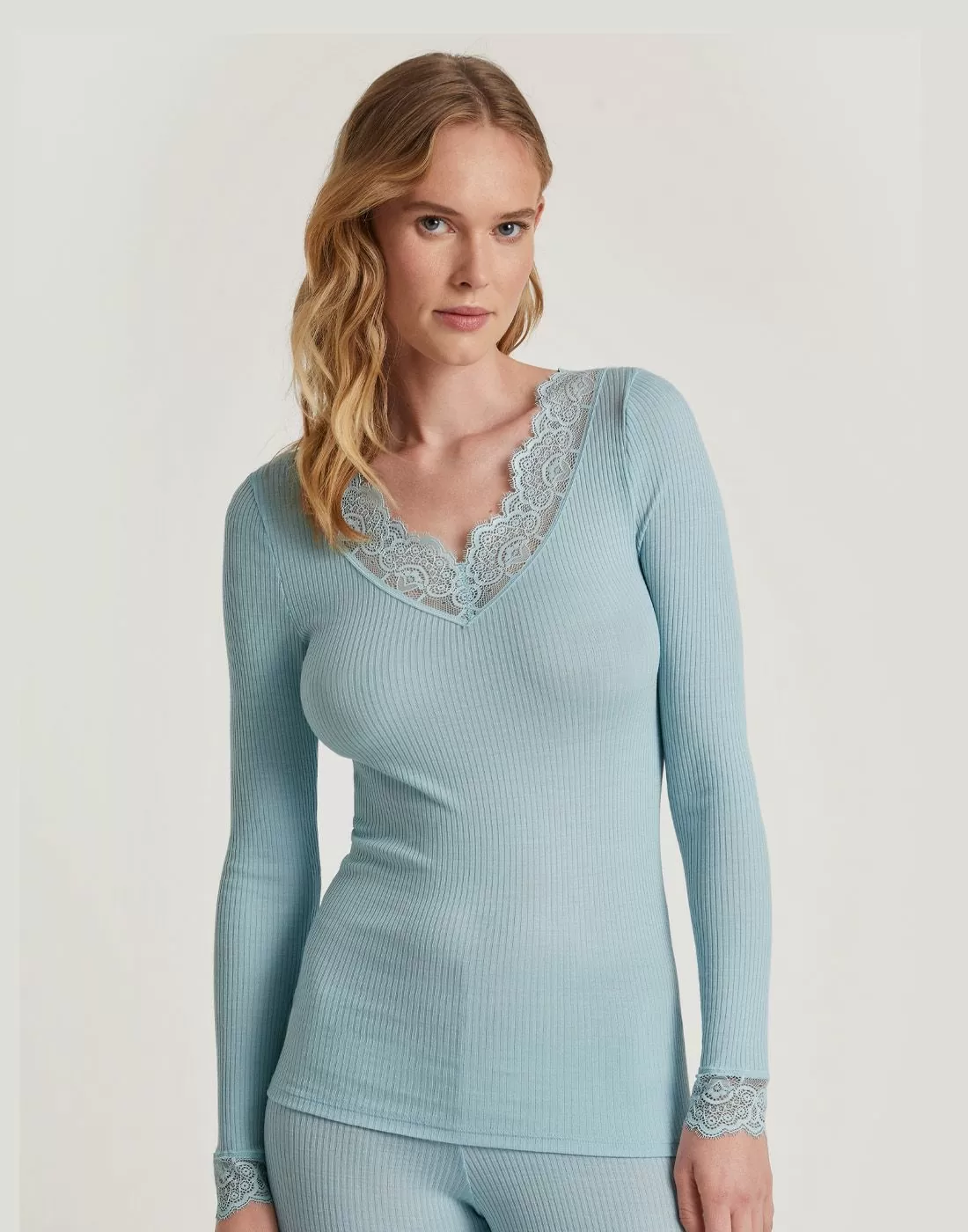 blond kvinne i blå ull og silke genser med blonder