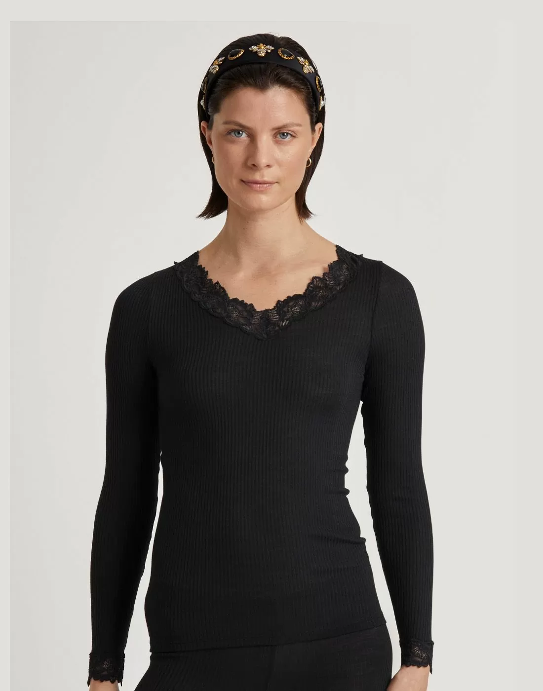 kvinne med kort brunt hår i svart ull og silke genser med blonder